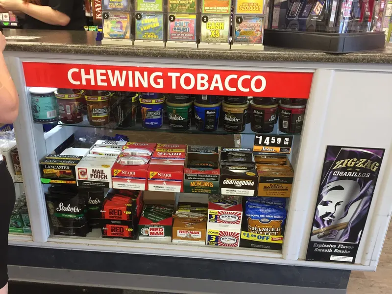 Our Chewing Tobacco case is stacked with all the regulars, Longhorn, Stoker's, Red Man, and Beech-Nut, along with Zig-Zag cigarillos on the side. Whether you dip or chew, we keep the shelf full so you're never stuck without your brand. Chewing tobacco display with Longhorn, Stoker's, and Red Man tins and pouches at GS Vape in Barberton, Ohio.