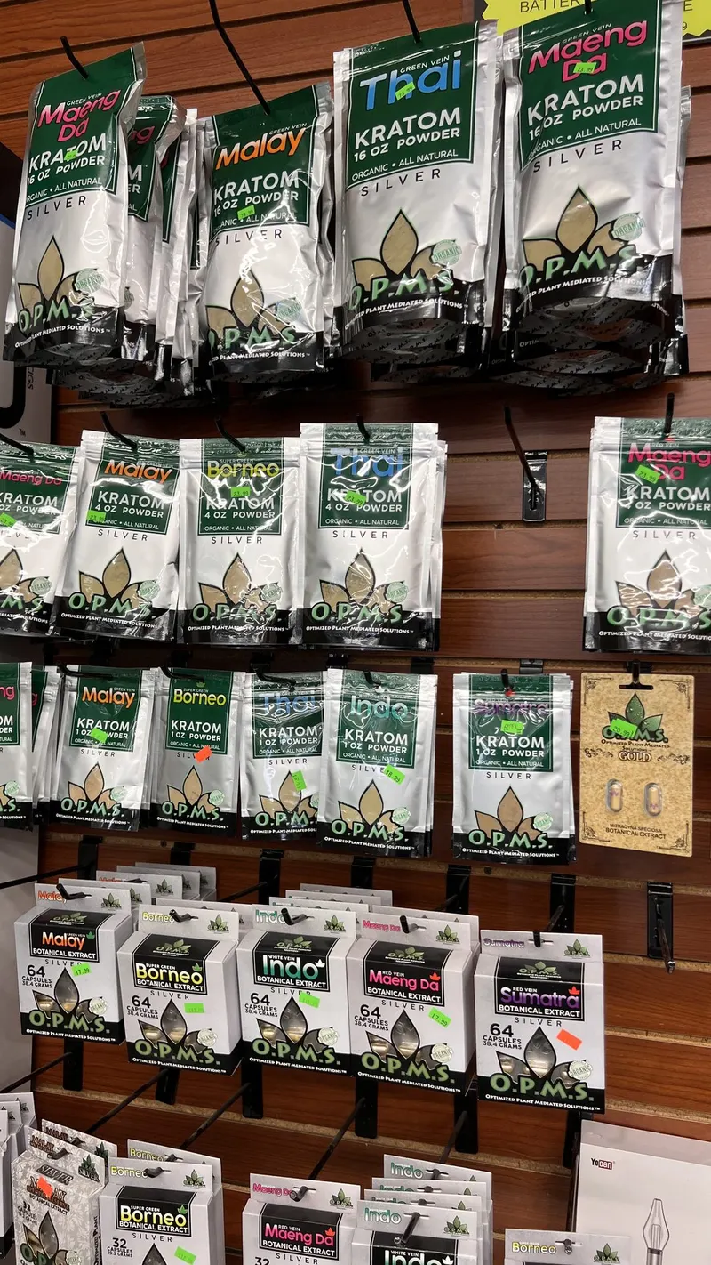 Wall display of OPMS kratom powder pouches and capsules in various strains at GS Vape in Barberton, Ohio