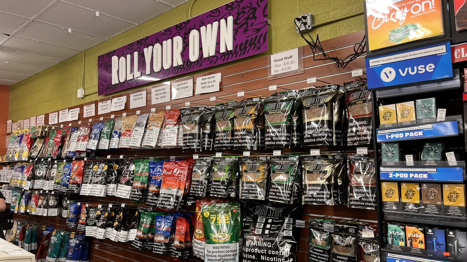 Roll Your Own tobacco sign above shelves of pipe tobacco and Vuse vape pods at GS Vape in Barberton, Ohio