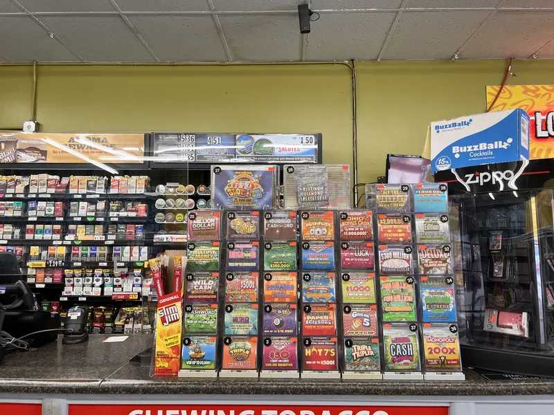 Our checkout counter features a full wall of Ohio Lottery scratch-off tickets alongside chewing tobacco and Slim Jim snacks. It's a convenient add-on stop whether you're already buying vape supplies or just grabbing lottery tickets on your way through town. Wall of Ohio Lottery scratch-off tickets above the checkout counter at GS Vape Beer & Tobacco in Barberton, Ohio.