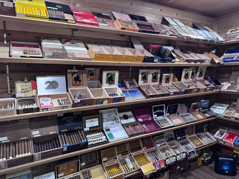 This wide shelf view inside GS Vape Madison's humidor room shows dozens of premium cigar boxes stacked and organized by brand. The room's depth reflects the store's commitment to a serious cigar selection. Wide shelf view of premium cigar boxes inside the humidor room at GS Vape in Madison, Ohio