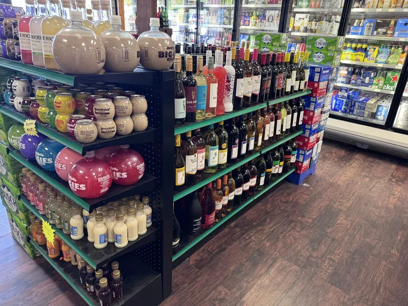 This shelf at GS Vape Madison features flavored moonshine and cocktail jars alongside an assorted wine selection. Beer coolers are visible in the background for customers building out a full order. Flavored moonshine jars and wine bottle display at GS Vape in Madison, Ohio