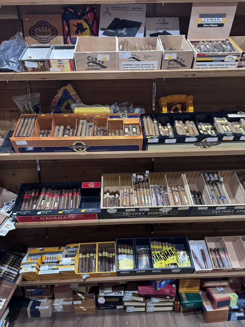 This shelf inside GS Vape Madison's humidor room features Havana Q, Quorum, and Mas Mas cigars organized by brand and size. Factory Smokes boxes below round out the selection for every budget. Premium cigar selection shelf featuring Havana Q and Mas Mas at GS Vape in Madison, Ohio