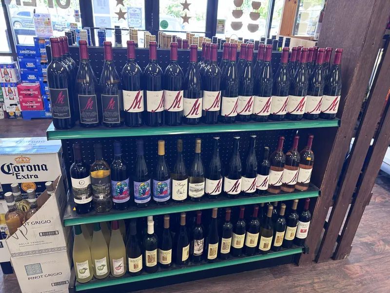 This premium red wine display at GS Vape Madison lines up a full row of bottles alongside boxed Pinot Grigio and Corona Extra. It's positioned near the front windows for easy browsing on the way in. Premium red wine bottle display at GS Vape wine shop in Madison, Ohio