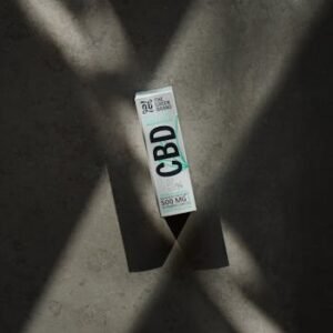 Minimalist shot of CBD oil packaging with artistic shadows emphasizing product focus.